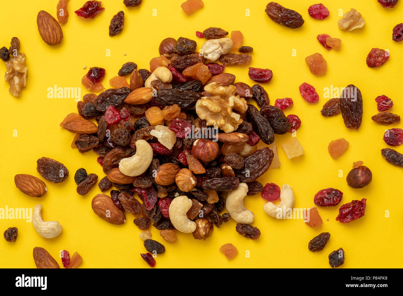 Close up of mix of dried fruits and nuts on a yellow background Stock Photo