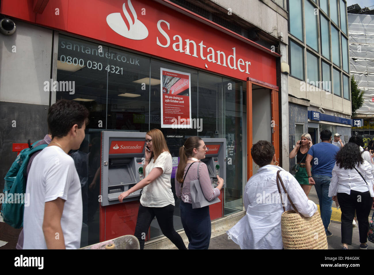 People walk past the Santander bank in Notting Hill, London, next to RBS. As part of a programme of closures this branch will close in October 2018. Stock Photo