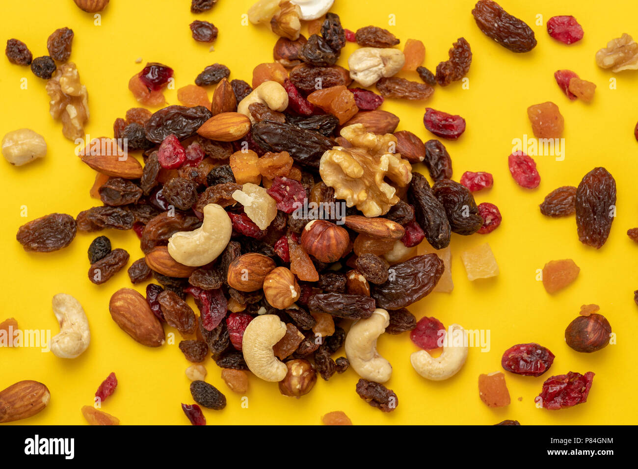 Close up of mix of dried fruits and nuts on a yellow background Stock Photo