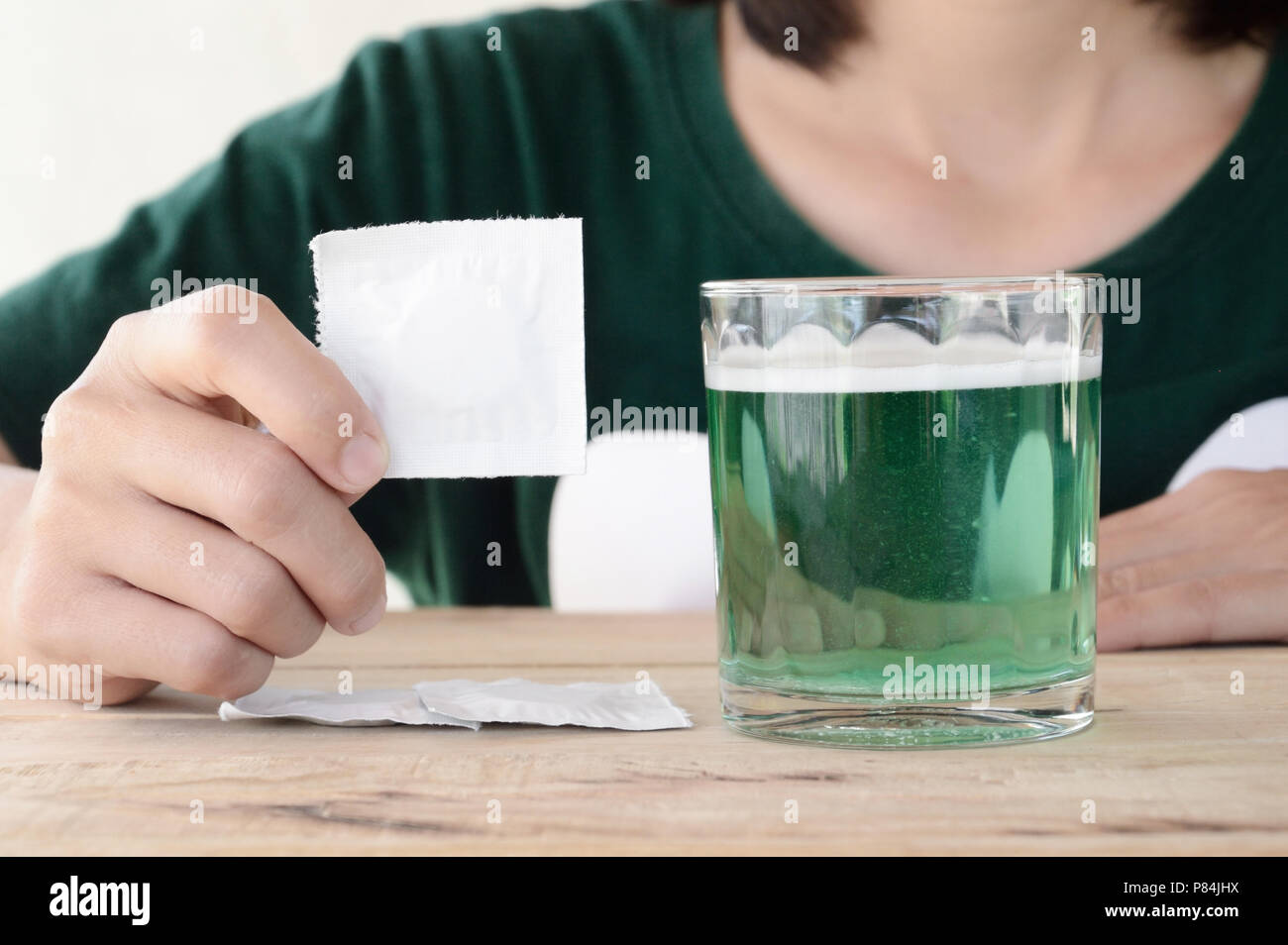 woman put effervescent tablet in glass of water on wooden table Stock Photo