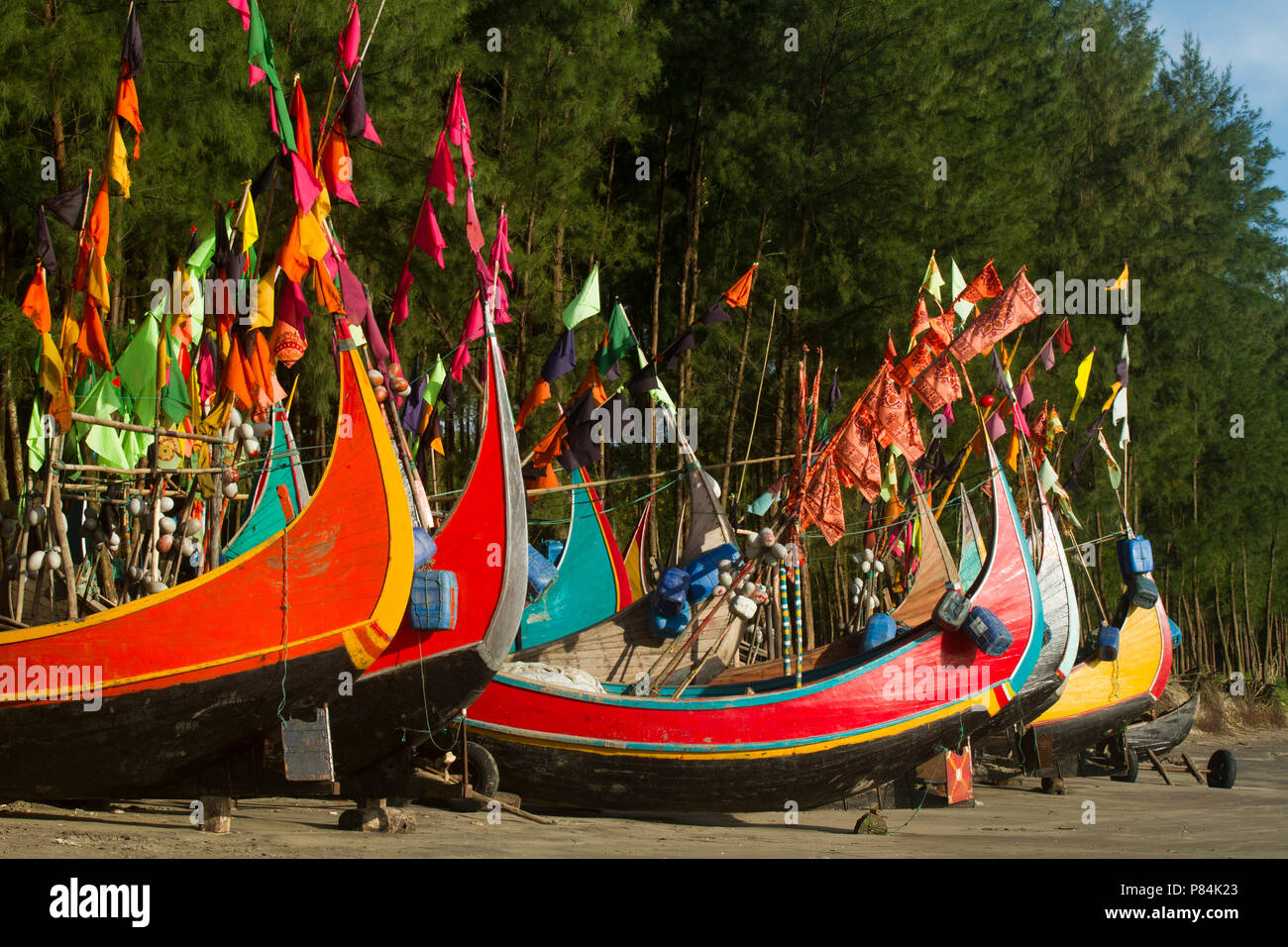 Colourful fishing boats with flags at the Teknaf Sea Beach. It is a part of the Cox's Bazaar Sea Beach, the longest sea beach in the world. Teknaf, Co Stock Photo