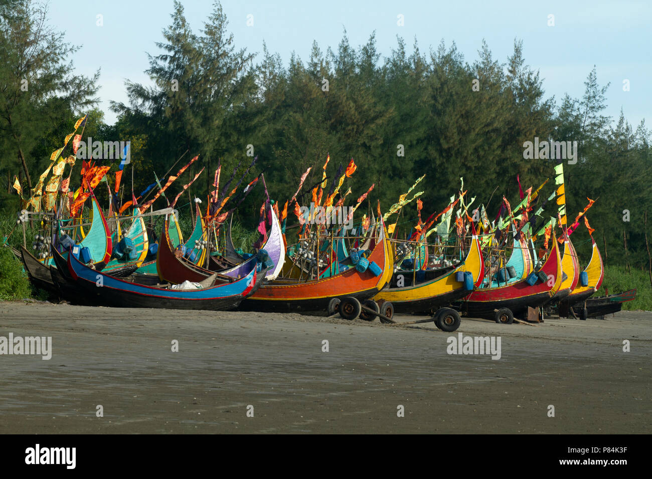 Colourful fishing boats with flags at the Teknaf Sea Beach. It is a part of the Cox's Bazaar Sea Beach, the longest sea beach in the world. Teknaf, Co Stock Photo