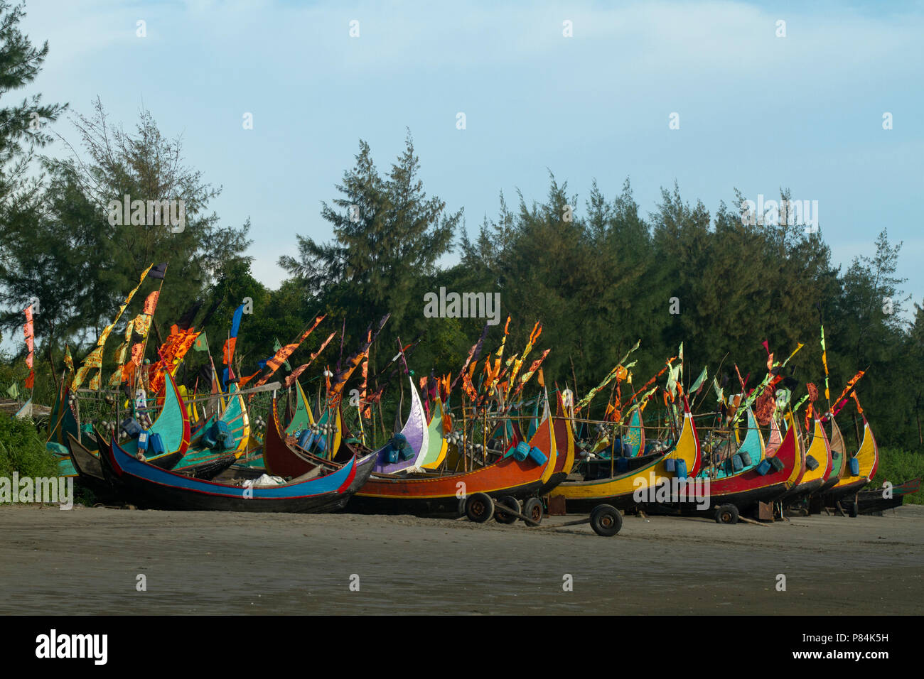 Colourful fishing boats with flags at the Teknaf Sea Beach. It is a part of the Cox's Bazaar Sea Beach, the longest sea beach in the world. Teknaf, Co Stock Photo