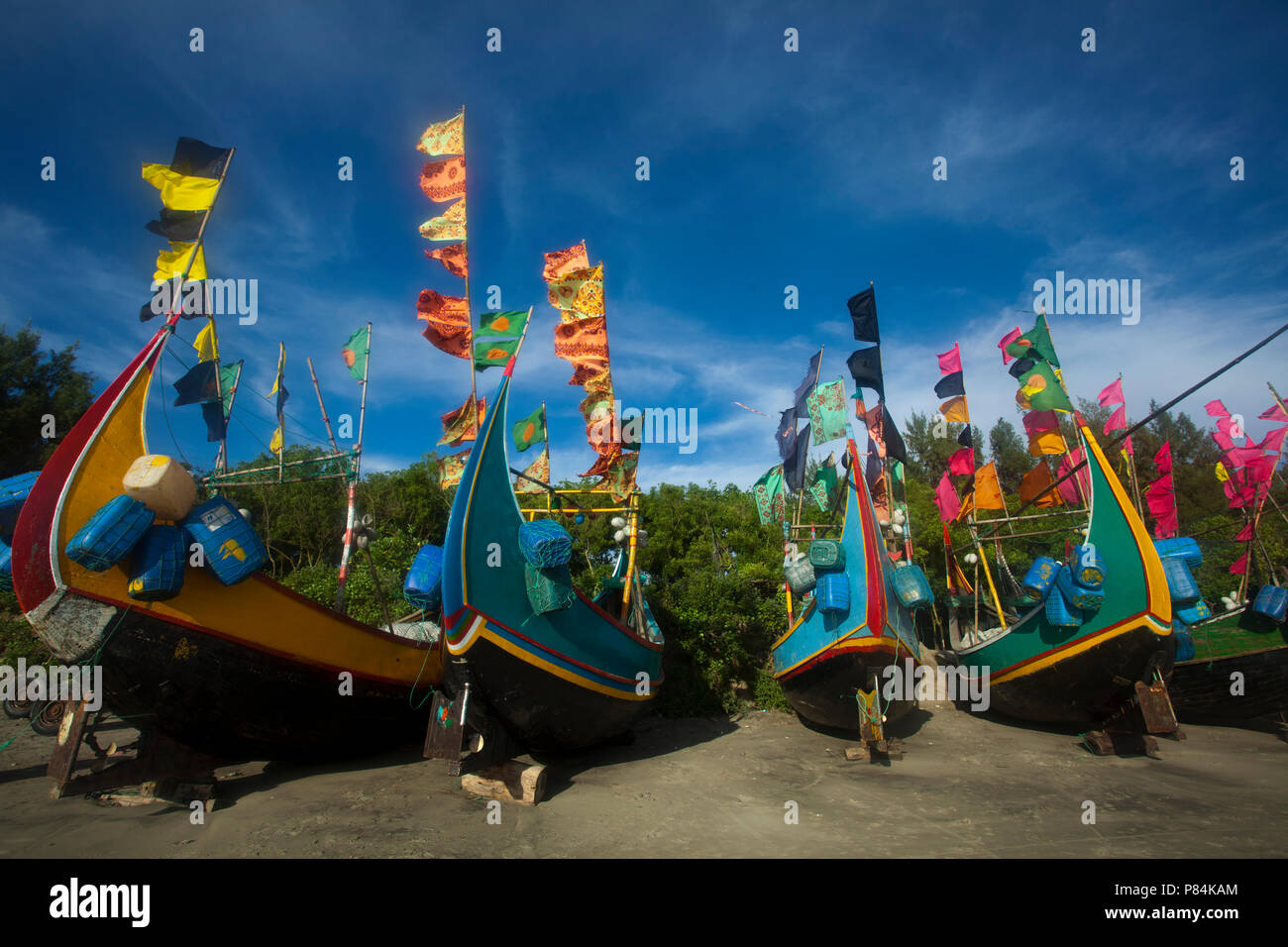 Colourful fishing boats with flags at the Teknaf Sea Beach. It is a part of the Cox's Bazaar Sea Beach, the longest sea beach in the world. Teknaf, Co Stock Photo