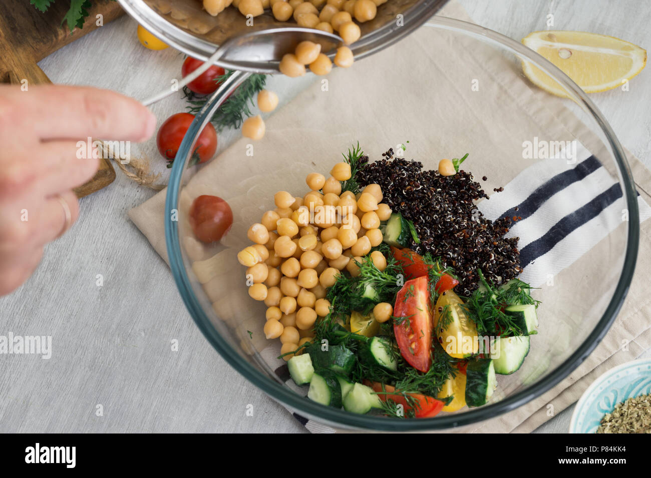 Cooking healthy food concept. Man preparing a salad of chickpeas, black quinoa and vegetables Stock Photo