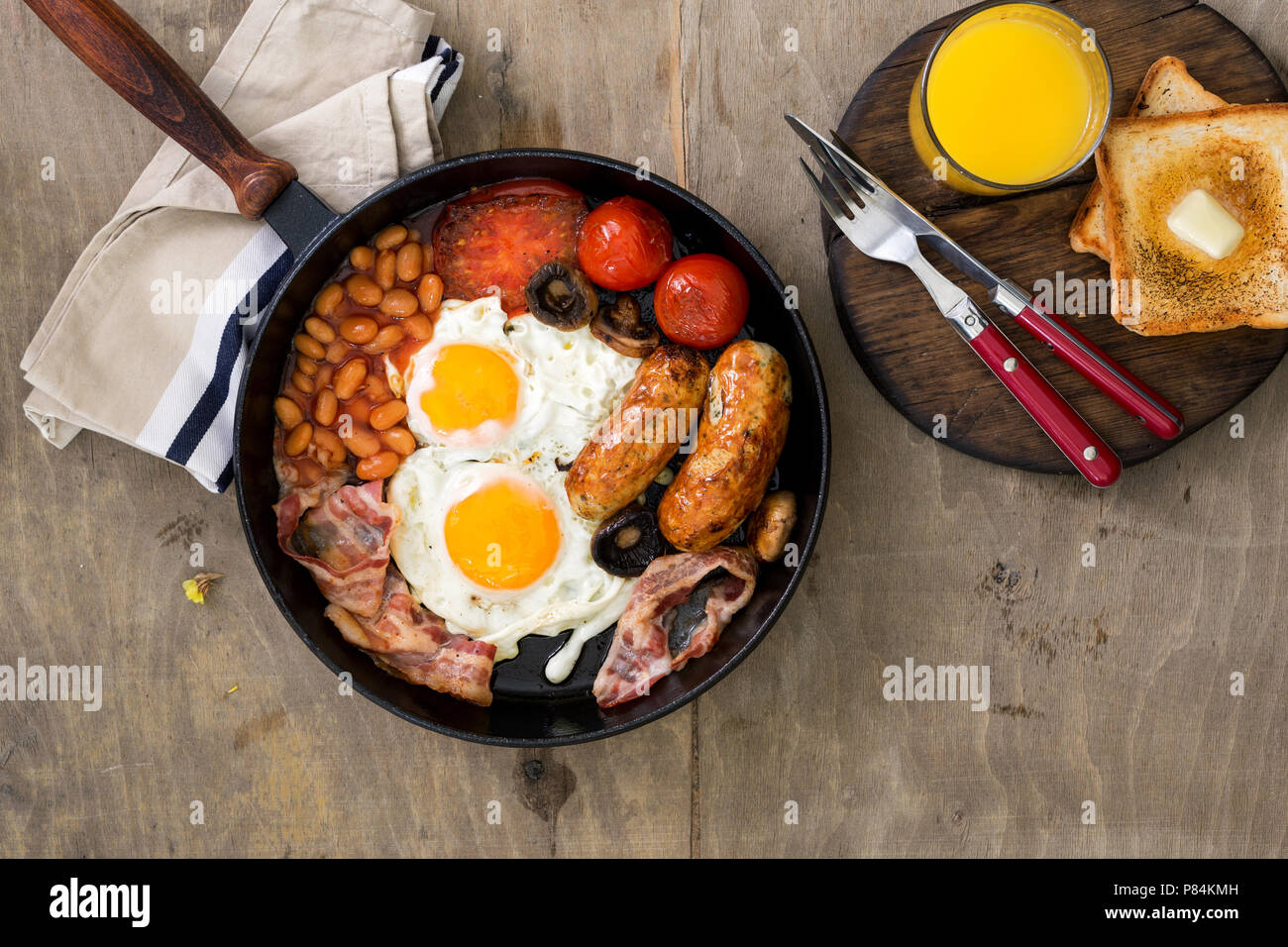 https://c8.alamy.com/comp/P84KMH/full-english-breakfast-in-a-cast-iron-frying-pan-on-a-wooden-light-table-top-view-P84KMH.jpg