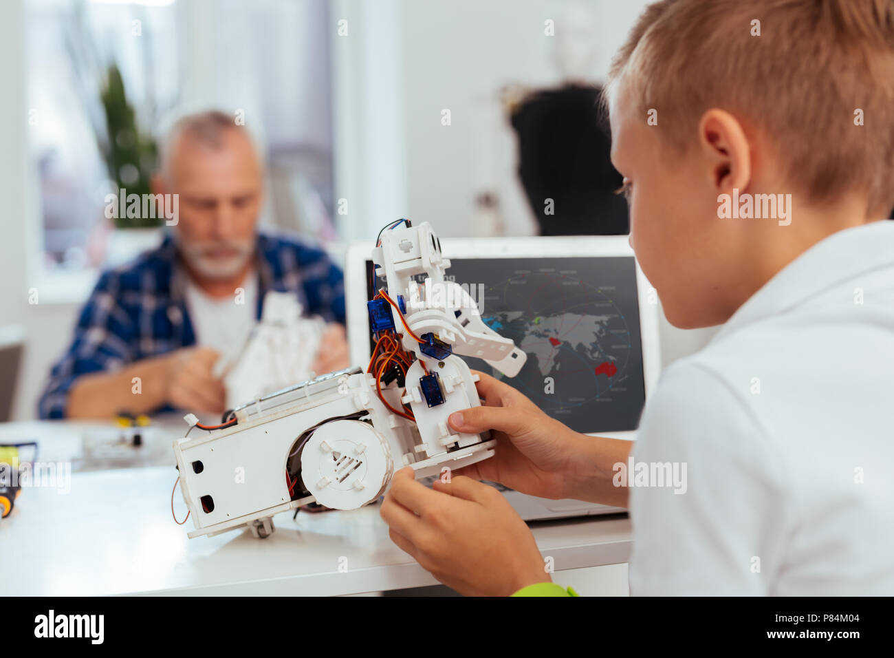Nice pleasant boy holding a small robot in his hands Stock Photo