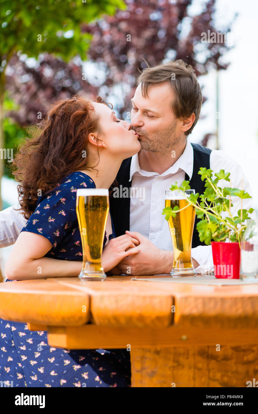 Man kissing woman in beer garden Stock Photo