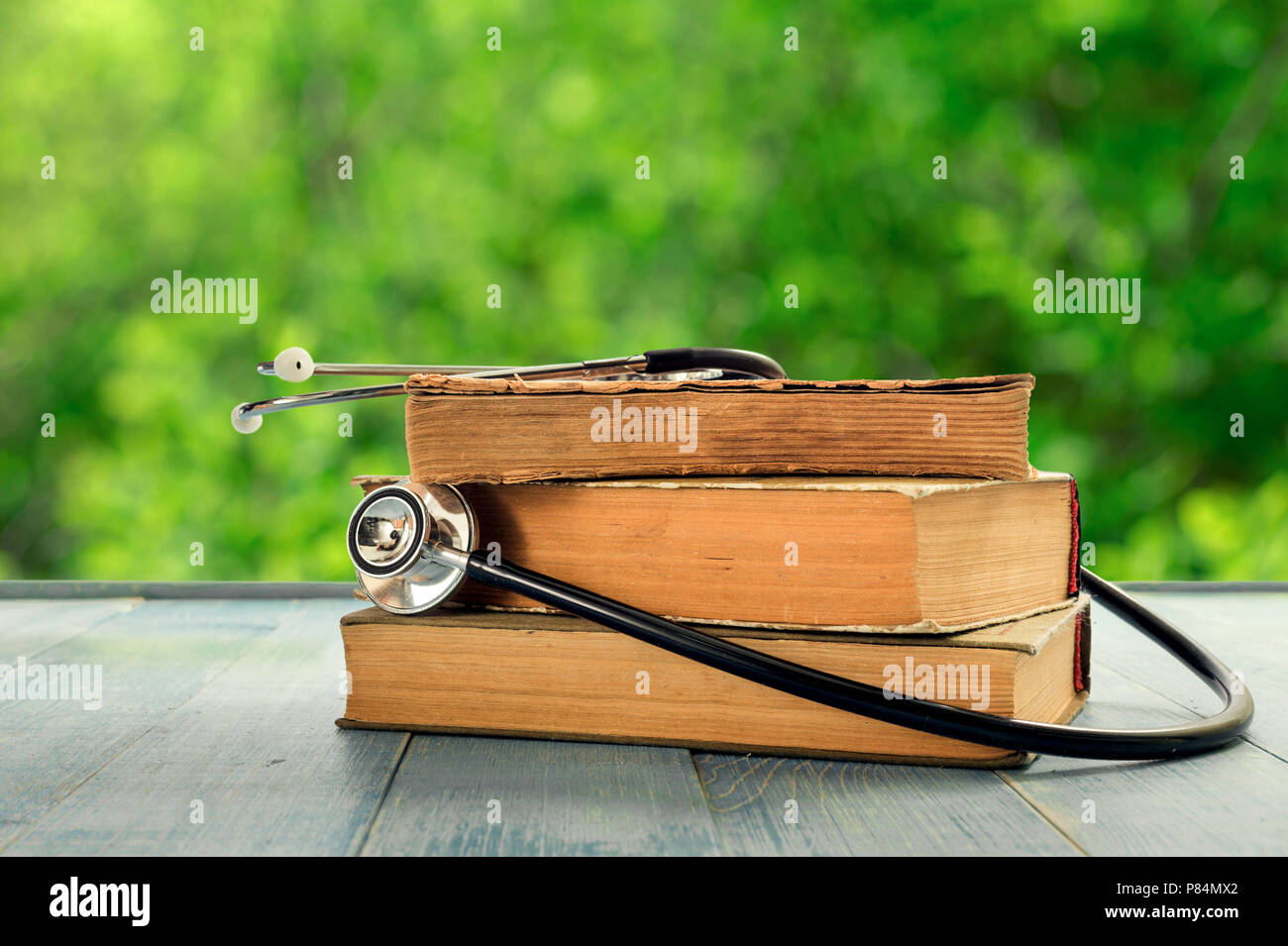 Stack of old books with stethoscope on wooden table against the ...