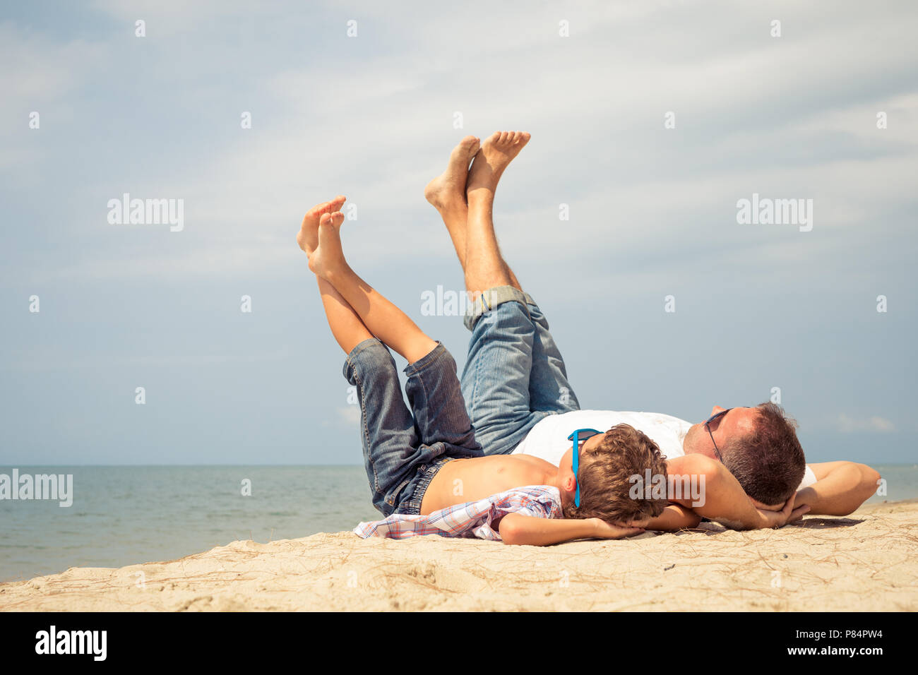 Father and  son playing on the beach at the day time. People having fun outdoors. Concept of summer vacation and friendly family. Stock Photo
