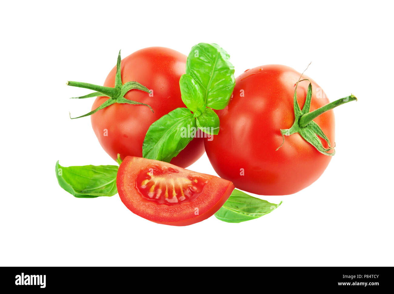Whole tomato with a slice of tomato and basil leaves on a white background closeup Stock Photo