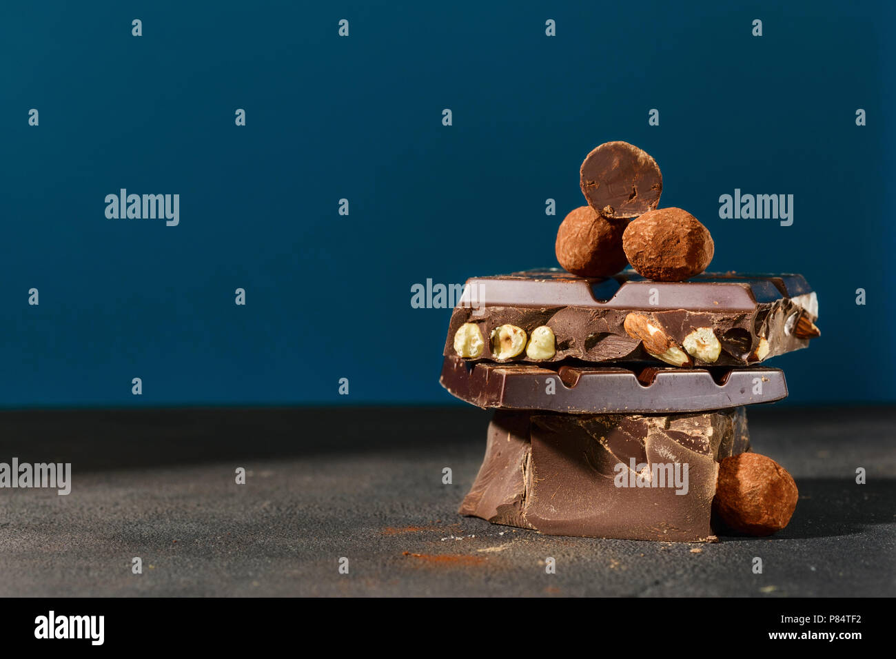Dark chocolate stack and truffle chocolates on blue background with copy space Stock Photo