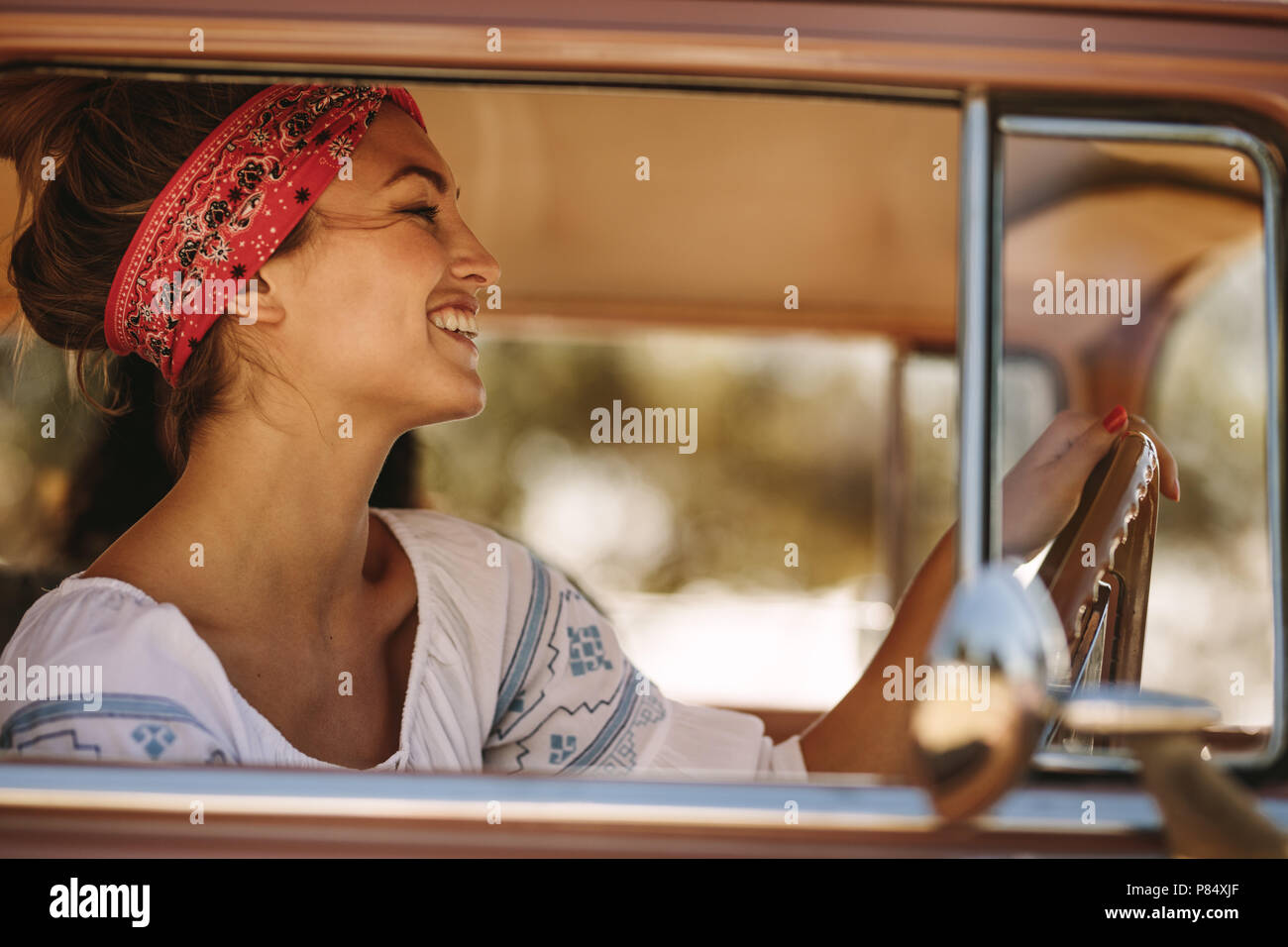 Side view shot of beautiful woman wearing bandana driving a car and  smiling. Caucasian female on road trip with friends Stock Photo - Alamy