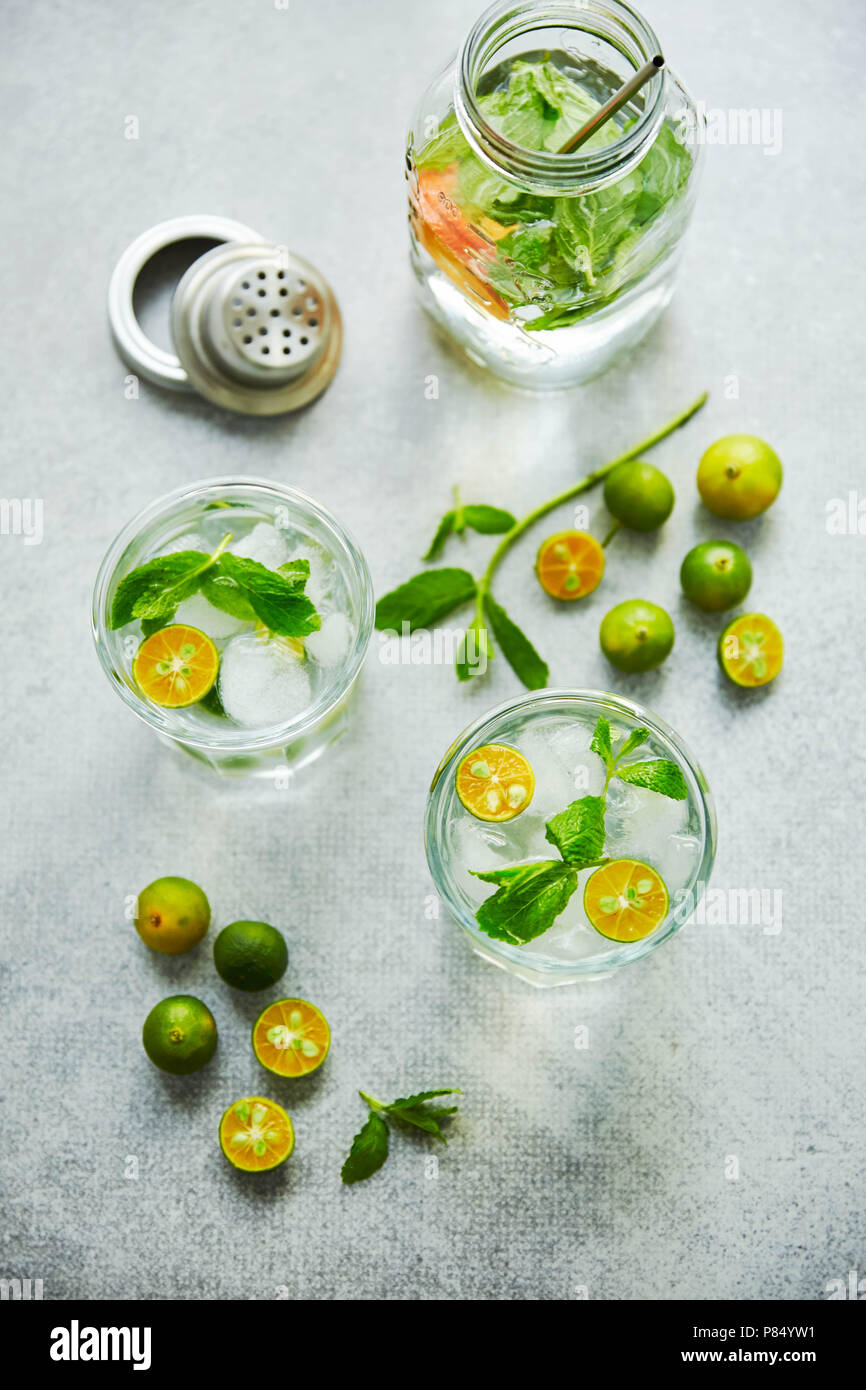 Gin and tonik cocktail with green calamondin and fresh mint leaf. Vertical top view. Stock Photo