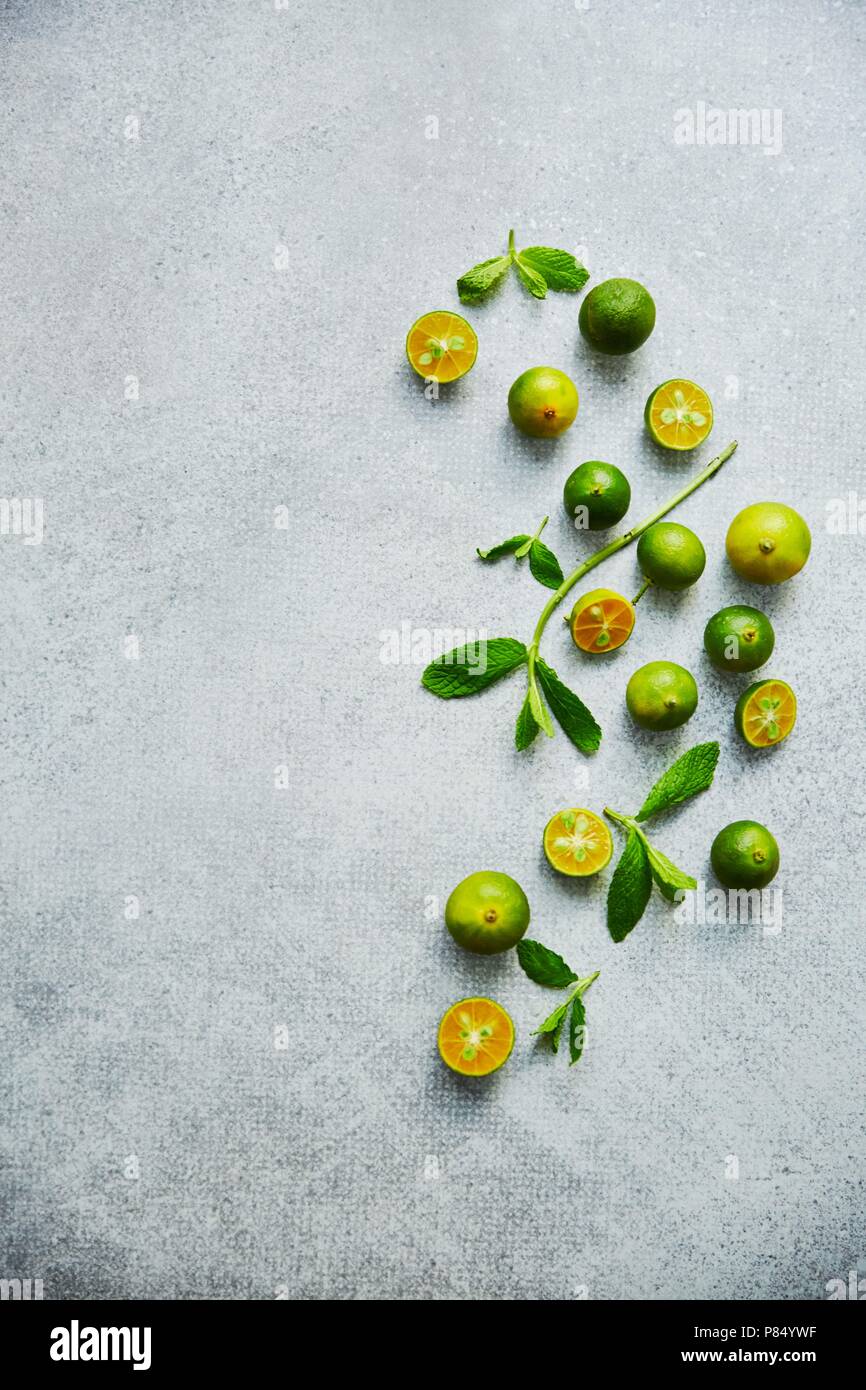 Green calamondin on grey background. Vertical food background, top view Stock Photo