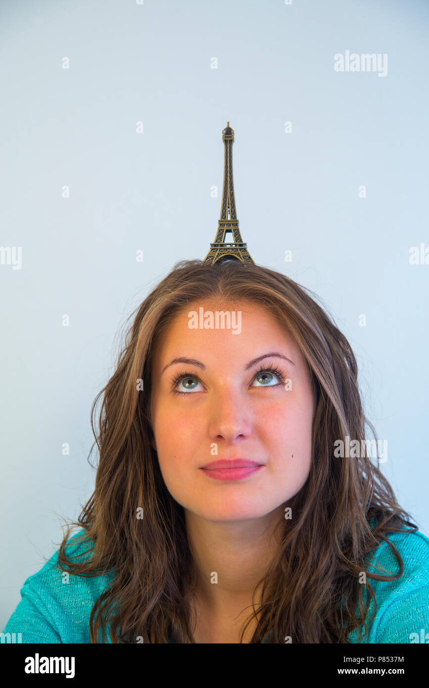 Young woman with a scale model of Eiffel Tower on her head. Stock Photo