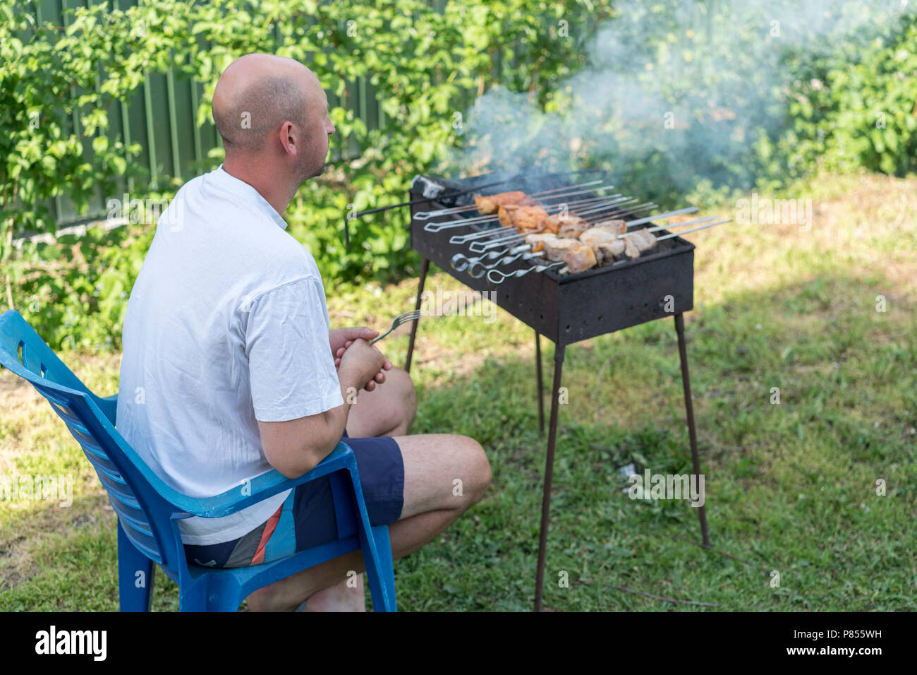 Man cooking meat on barbecue. Young couple making barbecue in their