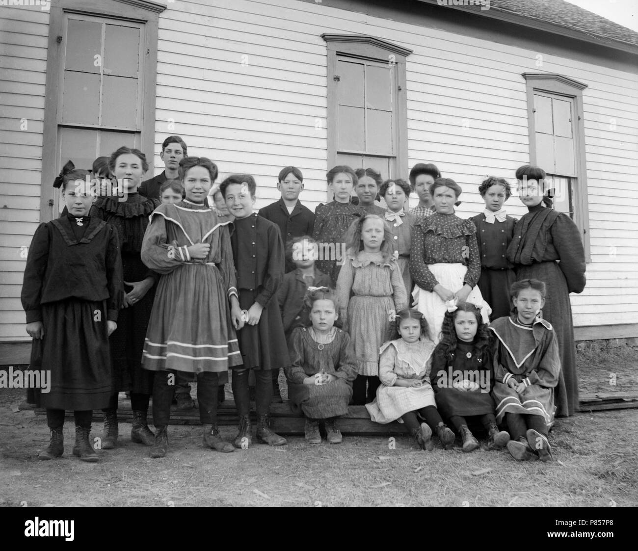 One-room schoolhouse students pose for a class photo on the American Great Plains, ca. 1905. Stock Photo