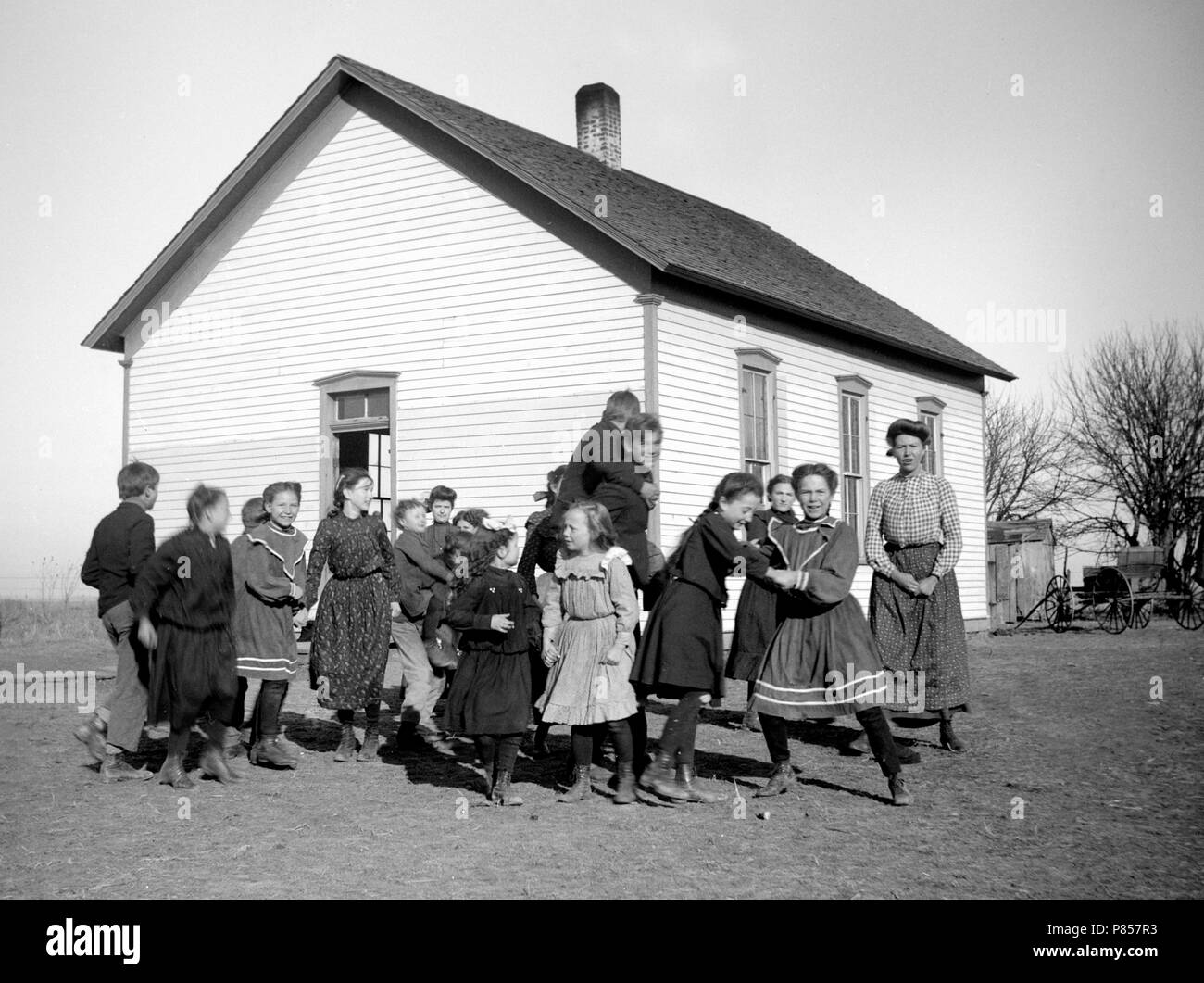 One-room schoolhouse students try to gather for a class photo on the American Great Plains, ca. 1905. Stock Photo
