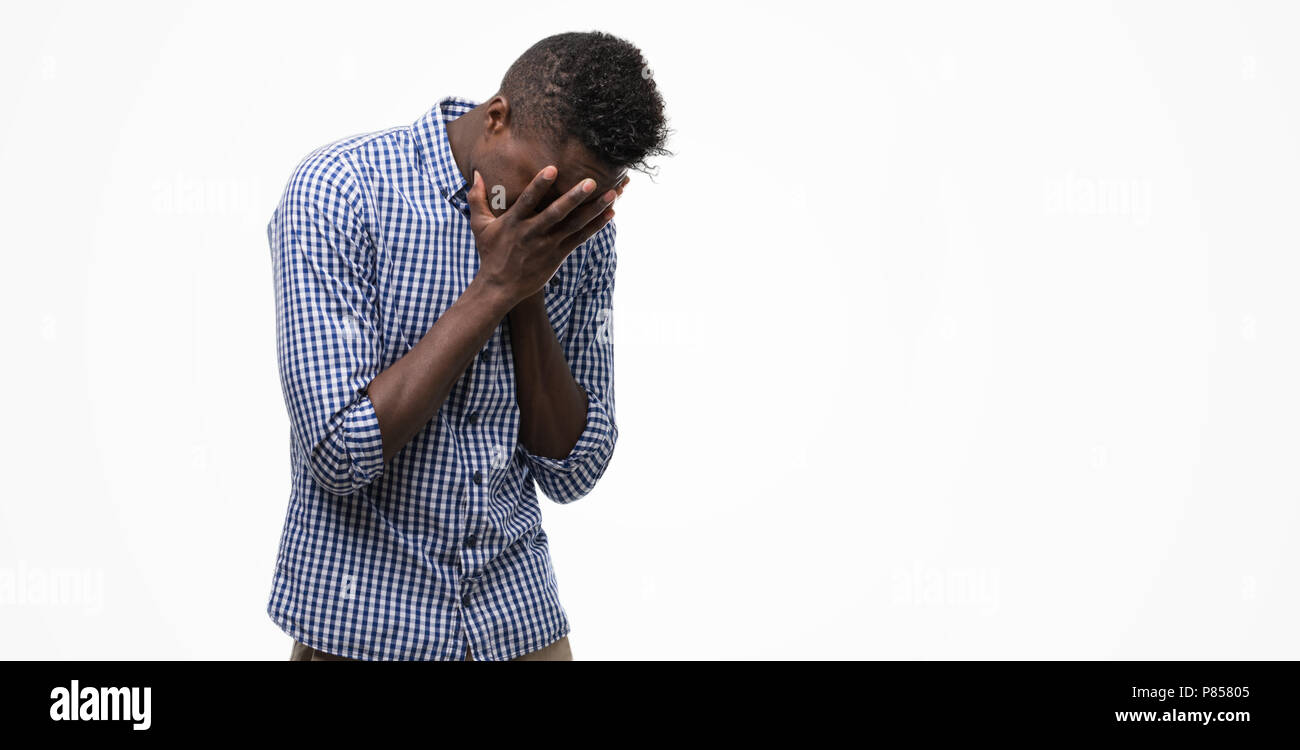 Young african american man wearing blue shirt with sad expression covering face with hands while crying. Depression concept. Stock Photo