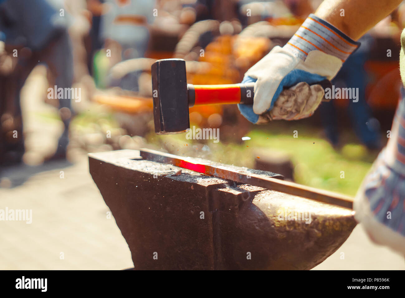 A blacksmith hammering a hot metal rod to shape it Stock Photo Alamy