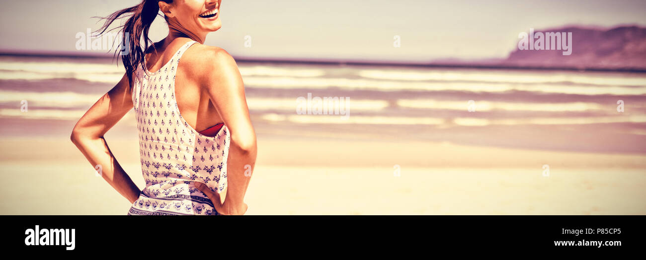 Portrait of happy woman with hands on hip standing at beach Stock Photo