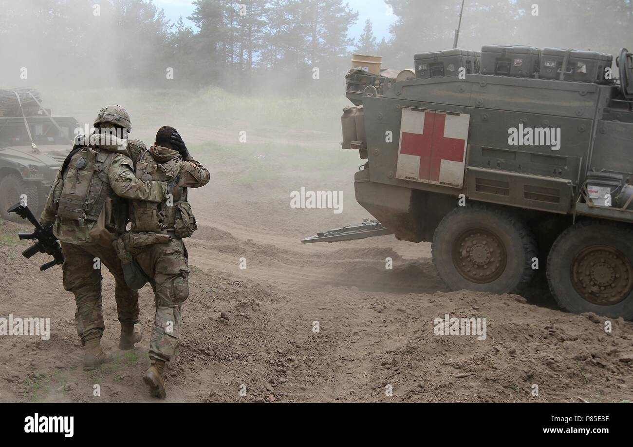 U.S. Army soldier from 2nd Platoon, Comanche Troop, 1st Squadron, 2nd Cavalry Regiment, Battle Group Poland, helps a simulated injured soldier to medical evacuation during a combat training exercise as part of their participation in Saber Strike 18 at the Bemowo Piskie Training Area, Poland on June 13, 2018, June 13, 2018. Saber Strike 18 is the eighth iteration of the long-standing U.S. Army Europe-led cooperative training exercise designed to enhance interoperability among allies and regional partners. (Michigan Army National Guard photo by 1st Lt. Erica Mitchell/ released). () Stock Photo