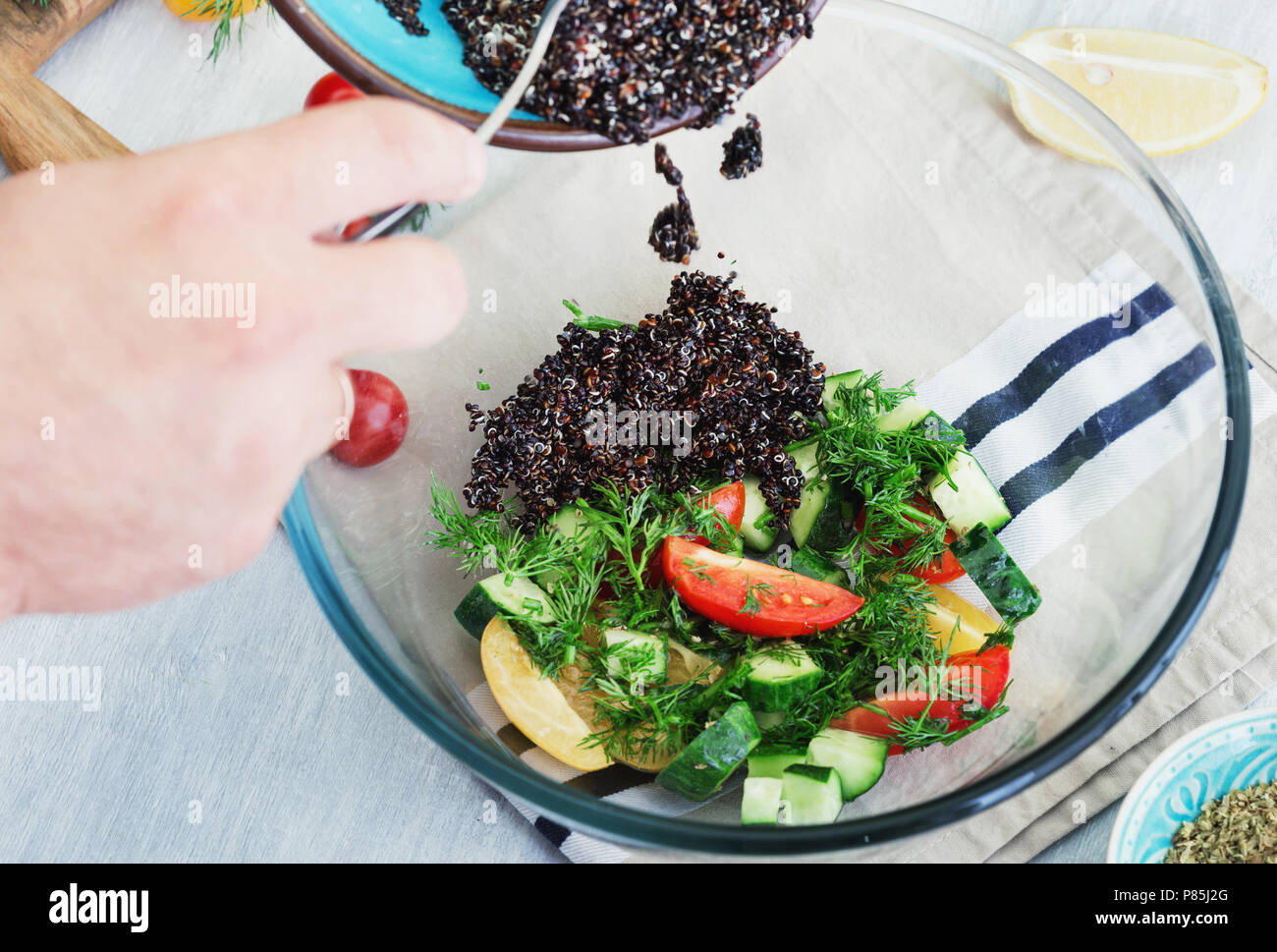 Cooking healthy food. Man preparing salad of black quinoa and vegetables Stock Photo