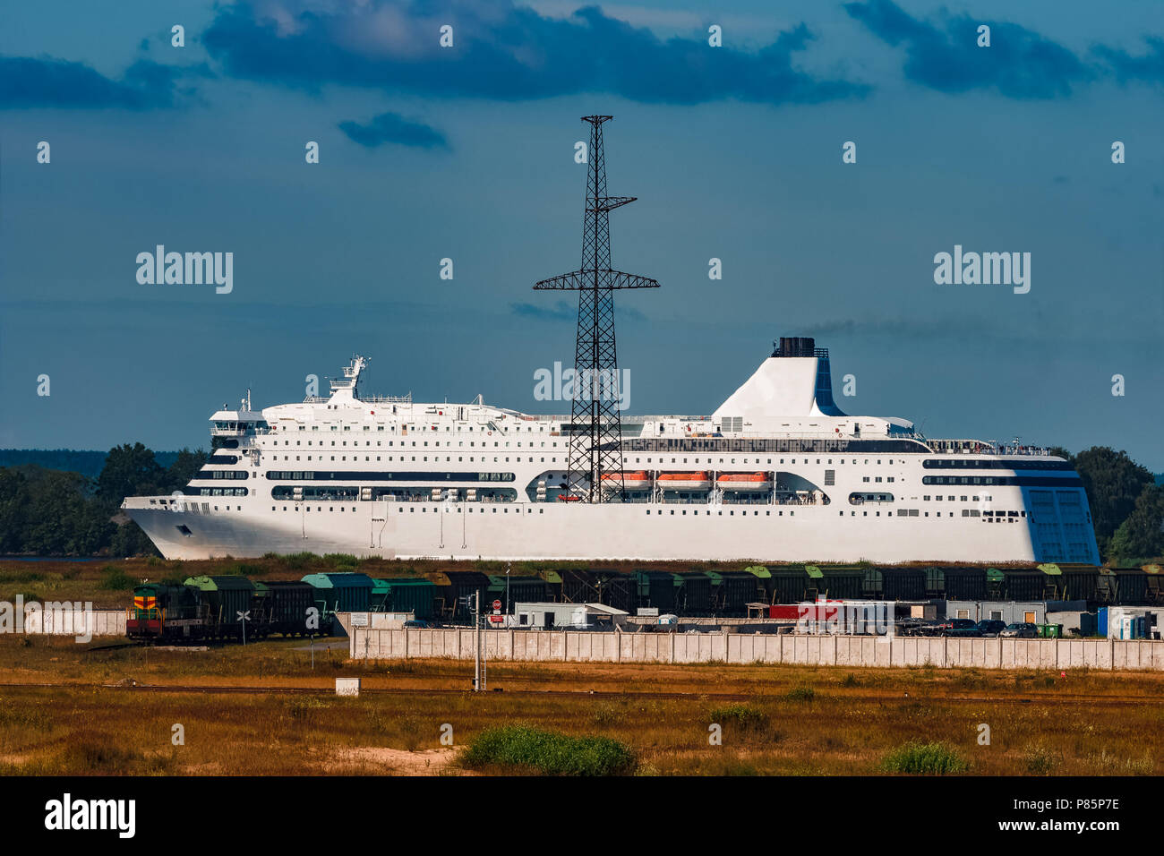 Small passenger ship moving past the cargo port at sunny day Stock Photo