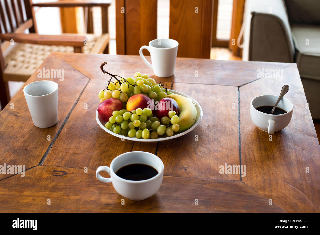 Summer food at hotel restaurant. Healthy diet with fruits: grapes, apples, coffee drink and peach on wood table. Stock Photo