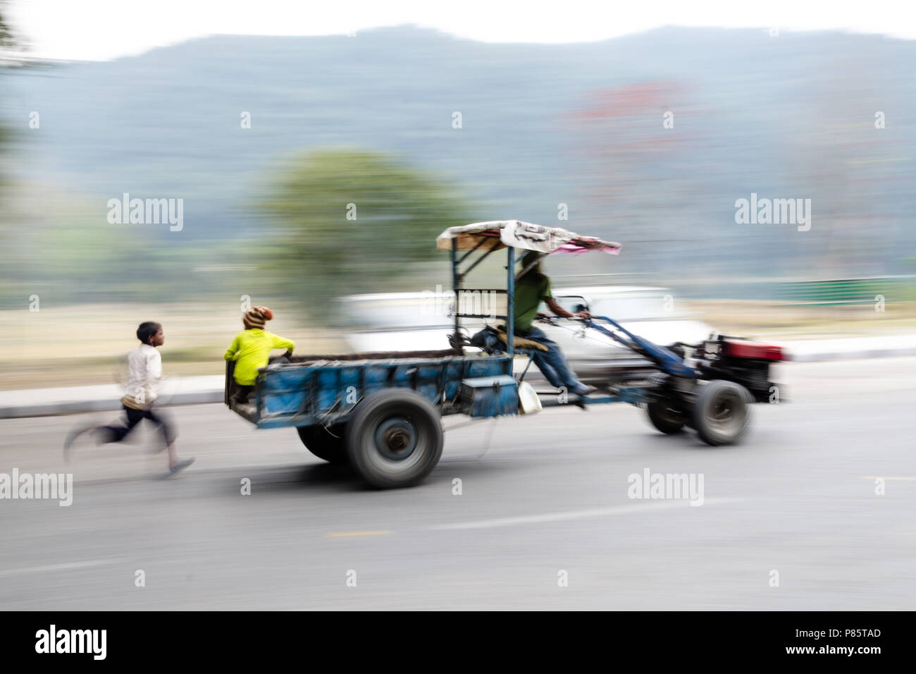 Panning shot of a boy running, trying to catch up to a truck, Pokhara, Nepal Stock Photo