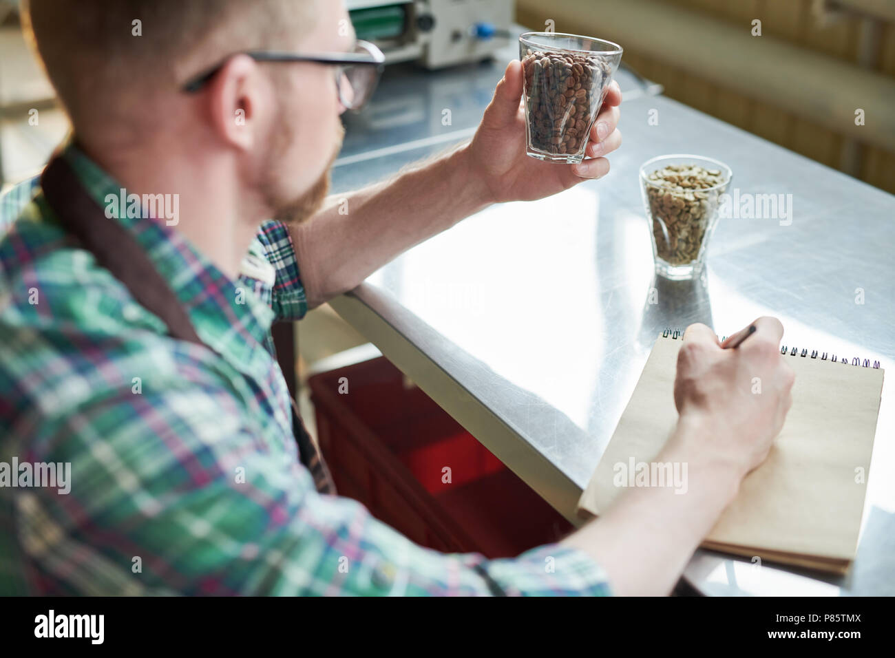 Over the shoulder view of modern barista holding coffee beans and ...