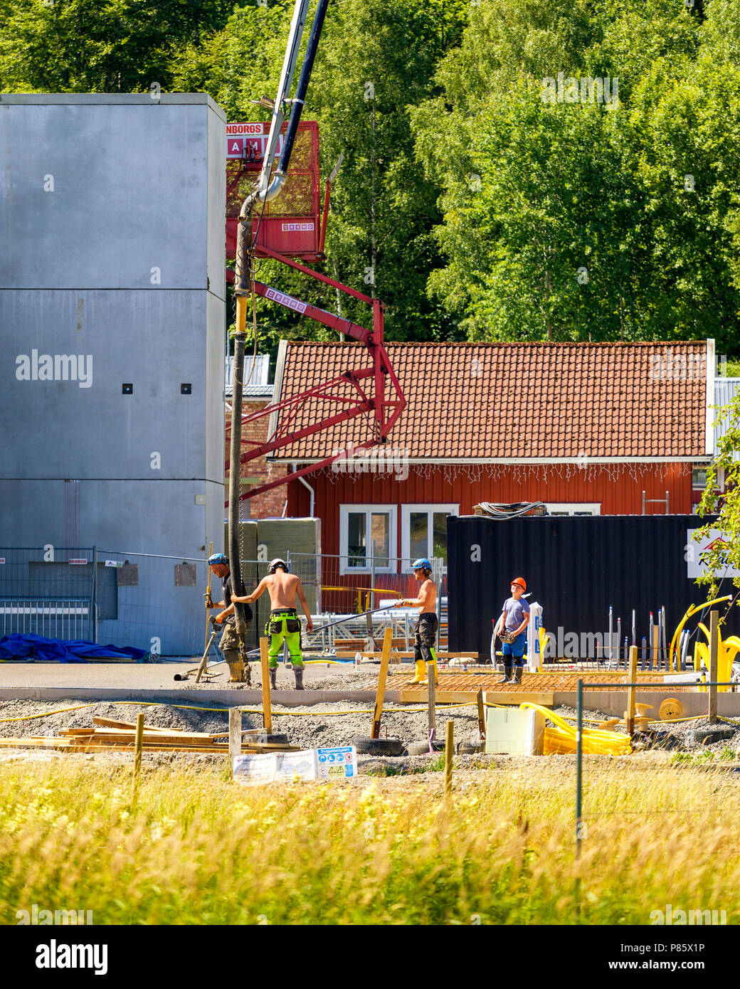 Builders working with very large crane pouring concrete at construction ...