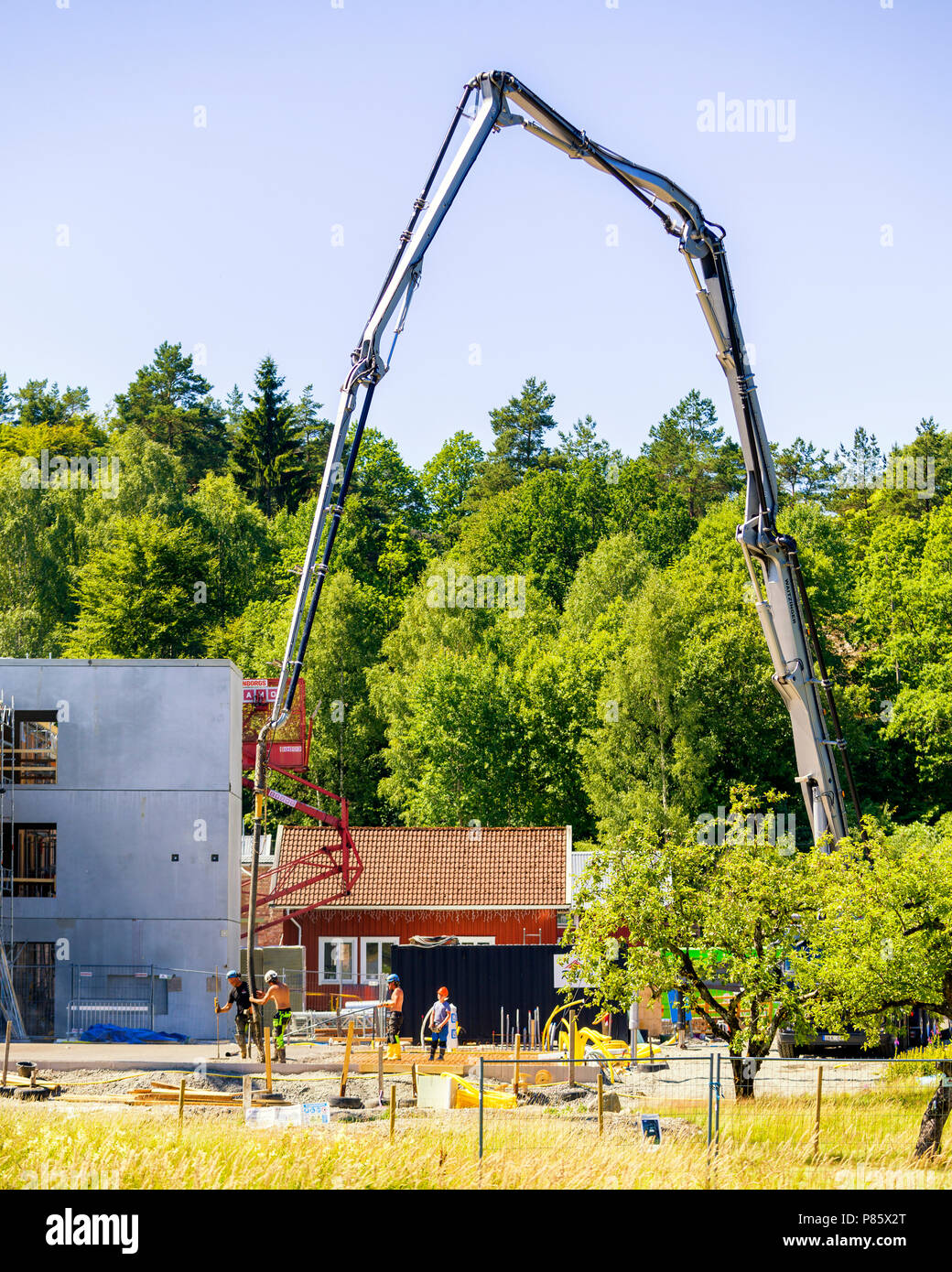 Builders working with very large crane pouring concrete at construction ...