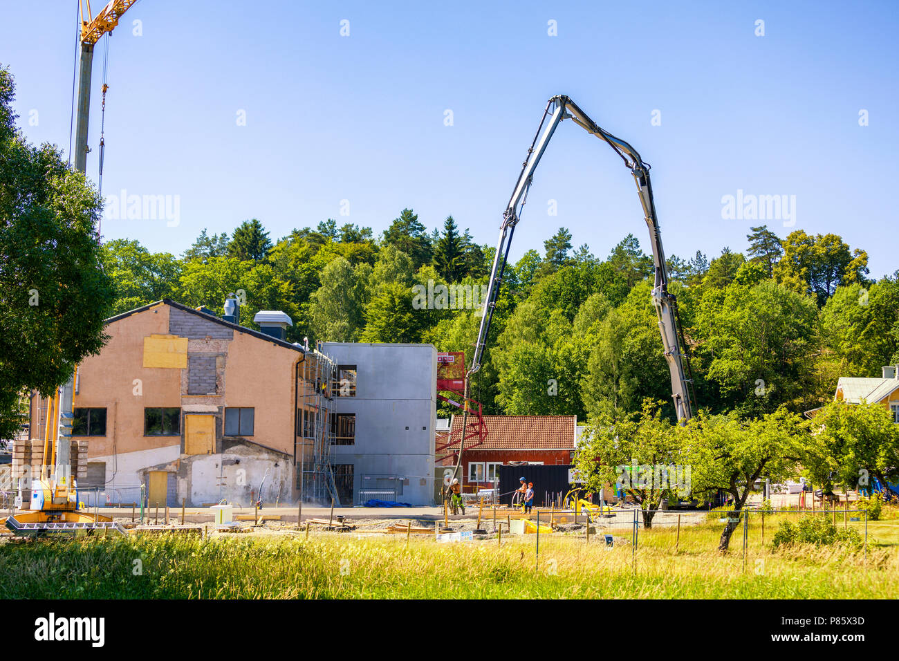 Builders working with very large crane pouring concrete at construction site Stock Photo