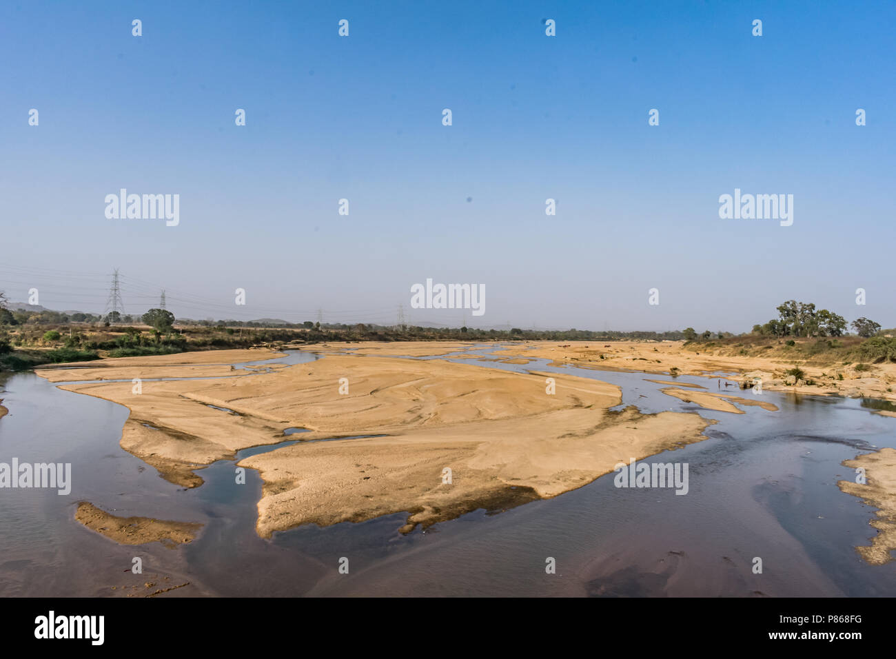 Indian river with clean water in sandy bed  with power grid cable laying background. Stock Photo