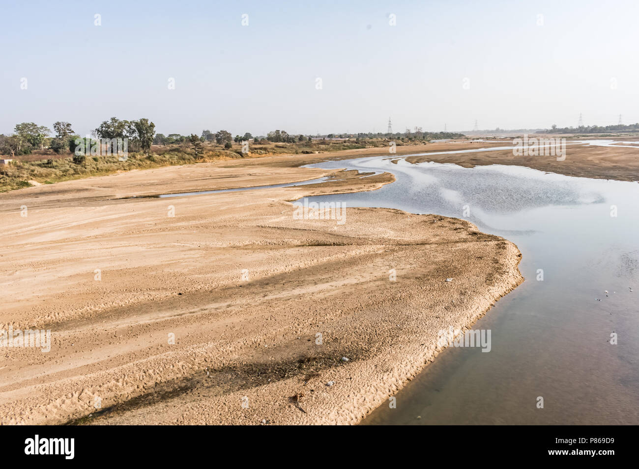 Indian river with clean water in sandy bed  with power grid cable laying background. Stock Photo