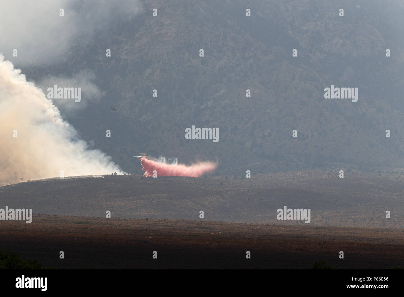 Alabama Hills, Lone Pine, CA. July 8, 2018. An air tanker deposits fire suppression material on the Georges Fire in the Alabama Hills west of Lone Pine, CA in eastern Sierra Nevadas.  The cause is under investigation. Lightning had been observed in the area. Fire crews from Inyo National Forest, the Bureau of Land Management (BLM),  CALFIRE, and local fire departments are fighting the fire with assistance from air tankers and helicopters. The helicopters are drawing water from the nearby California aquaduct. Stock Photo