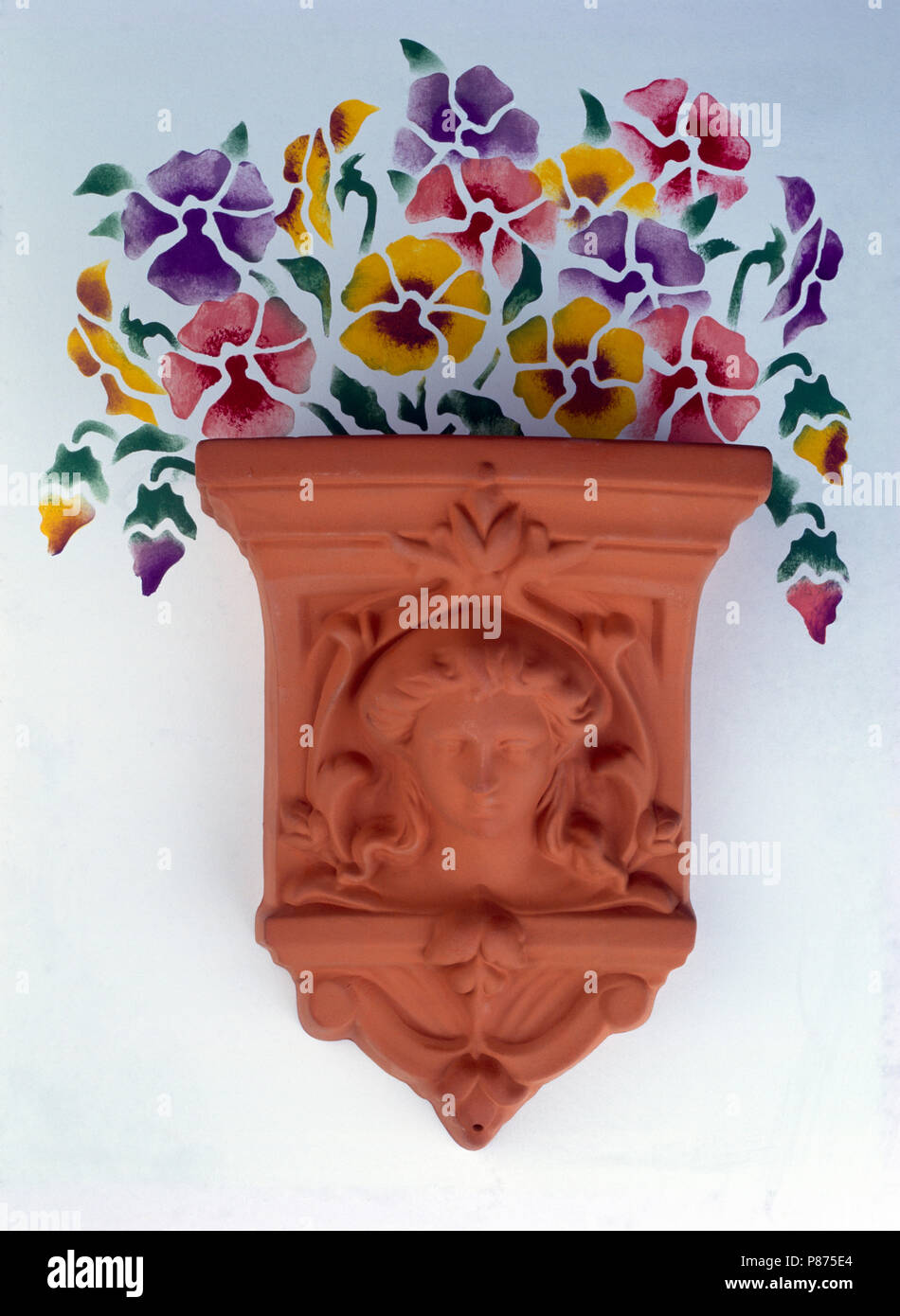 Close-up of stenciled pansies above a terracotta wall planter Stock Photo