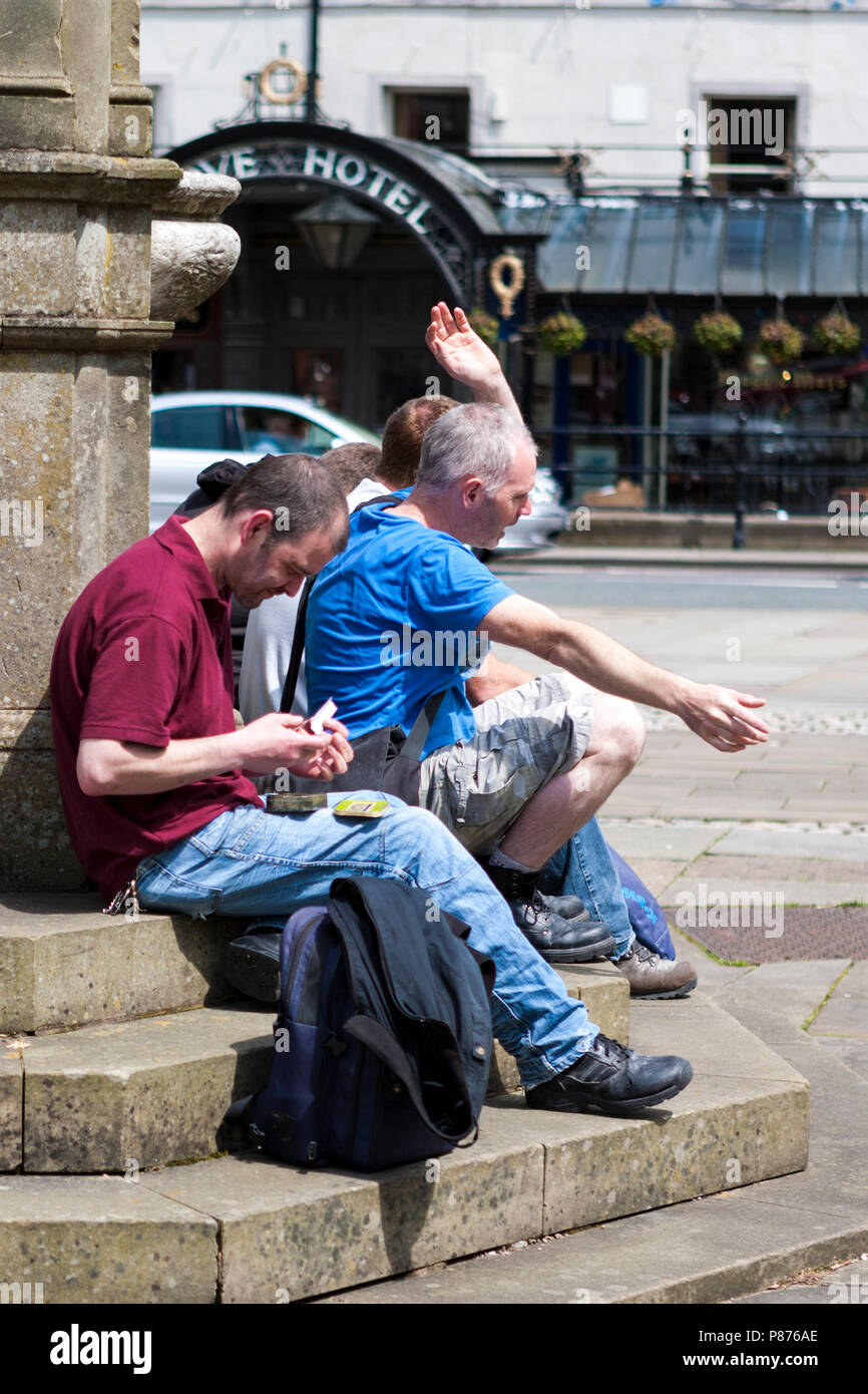 Drunks sit on the steps of the Samuel Turner Memorial Drinking Fountain , The Crescent, Buxton, Derbyshire, England, UK Stock Photo