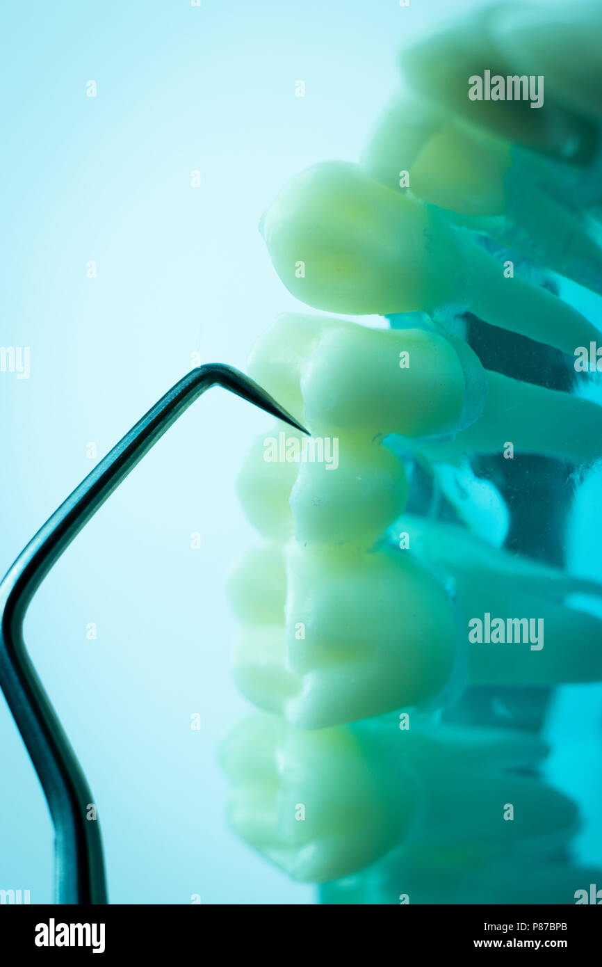 Dentist cleaning teeth with titanium metal tooth pick instrument to