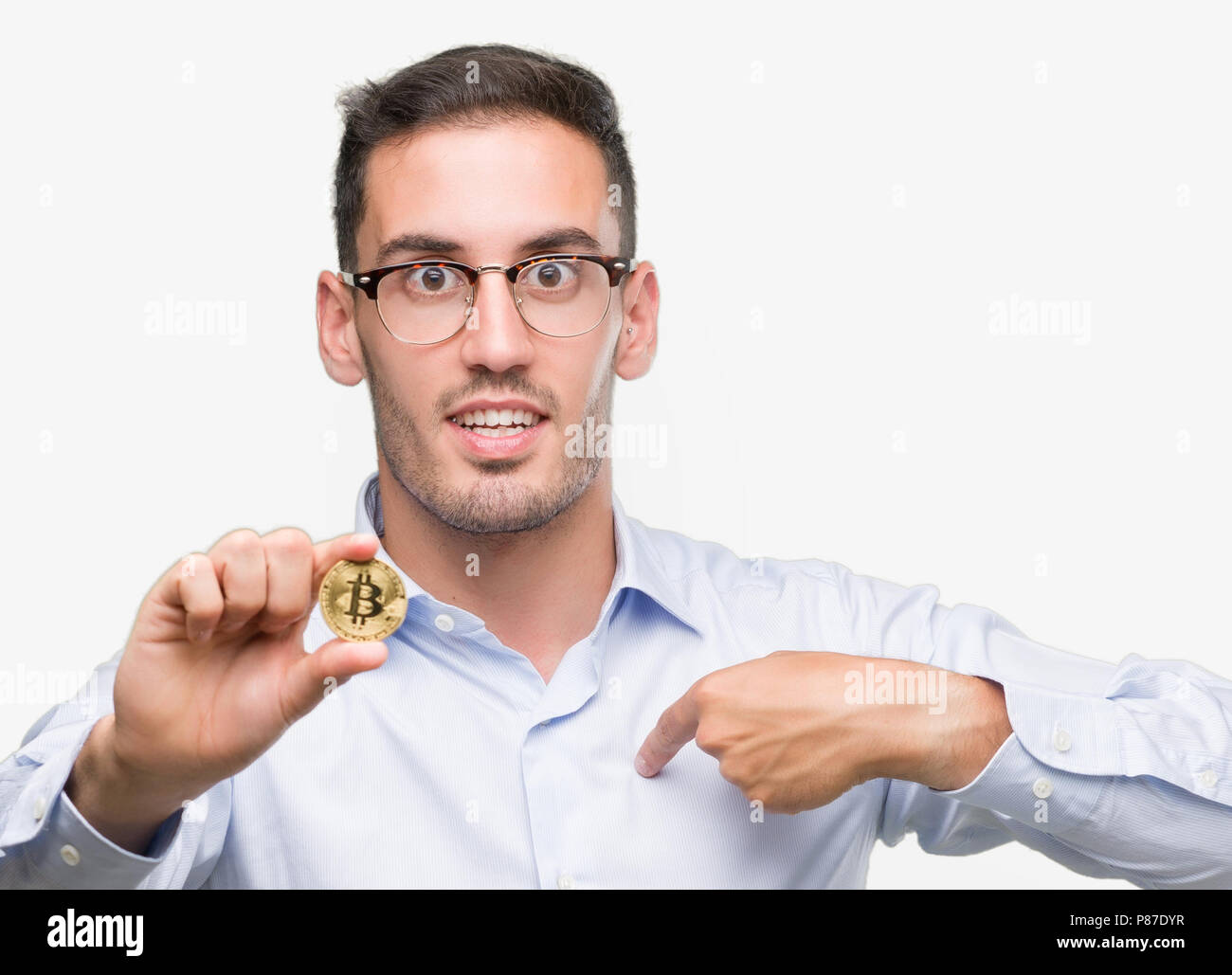 Handsome young man holding bitcoin with surprise face pointing finger to himself Stock Photo
