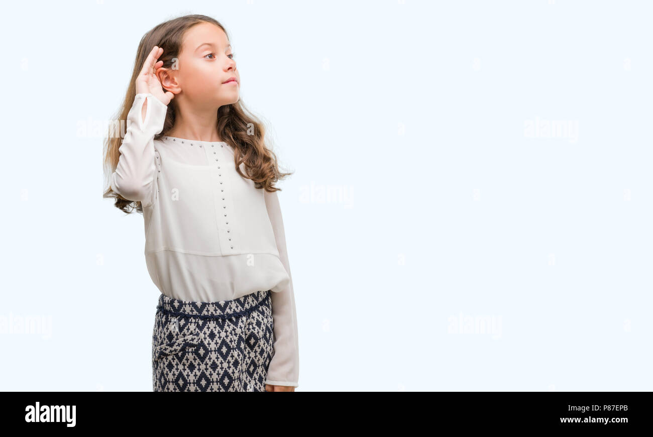 Brunette hispanic girl smiling with hand over ear listening an hearing to rumor or gossip. Deafness concept. Stock Photo