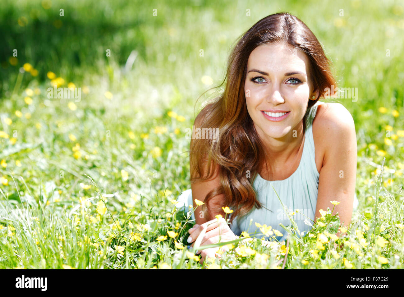 beautiful young woman in blue dress lying on grass Stock Photo - Alamy