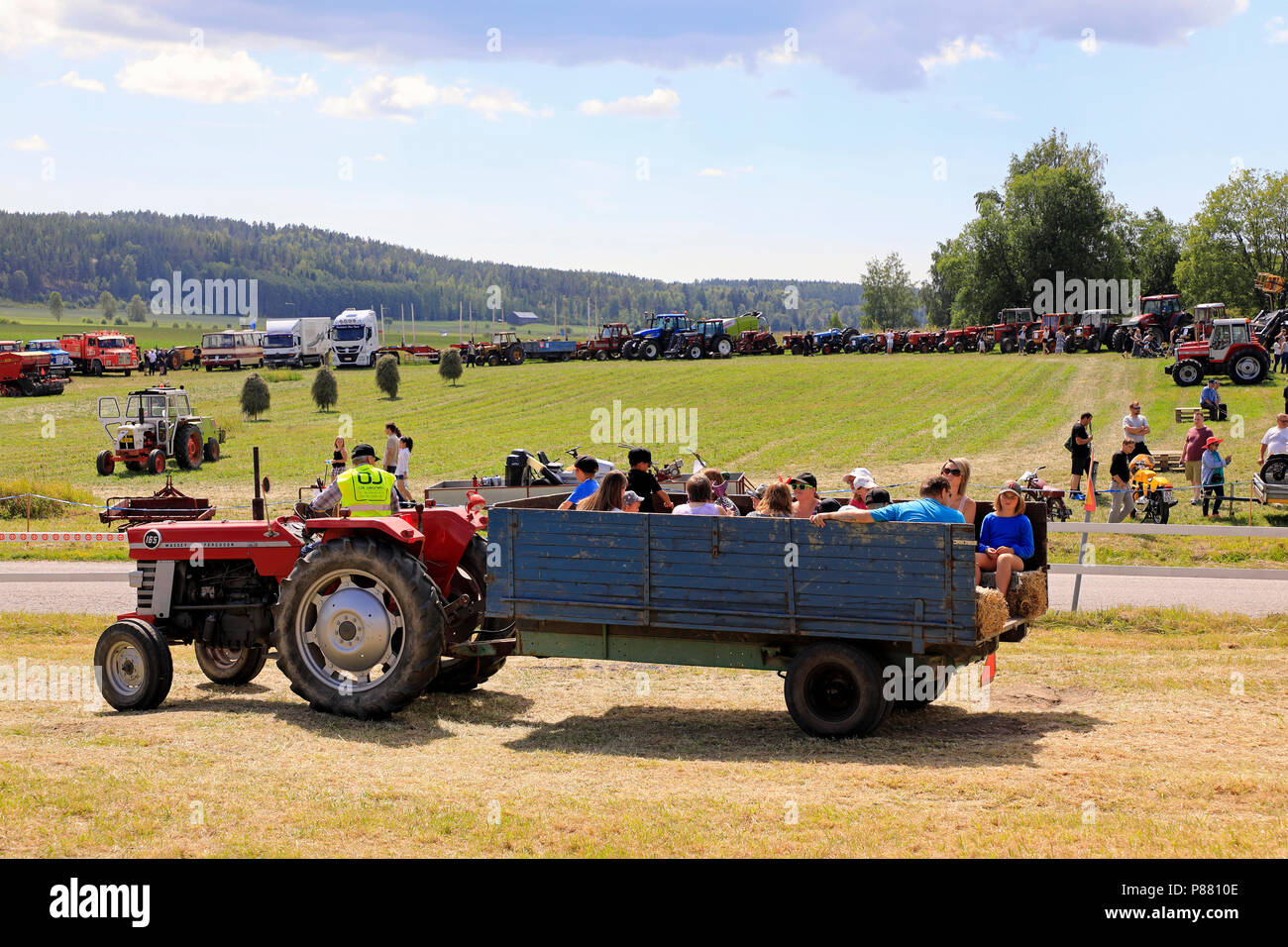Visitors are enjoying a tractor and trailer ride on Kimito Traktorkavalkad, Tractor Cavalcade, a tractor show in Kimito, Finland - July 7, 2018. Stock Photo