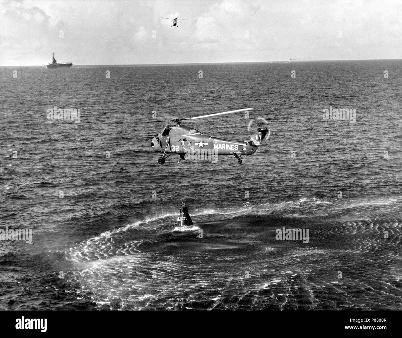 Attempted recovery of Mercury spacecraft at end of the Mercury-Redstone 4 (MR-4) mission. View shows the Marine helicopter dropping a recovery line to the capsule Stock Photo