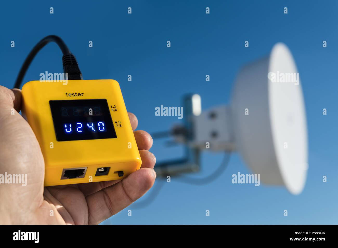 Diagnostics of outdoor wireless wifi receiver. Detail of hand holding measuring device to check a wi-fi access point for internet signal transmission. Stock Photo