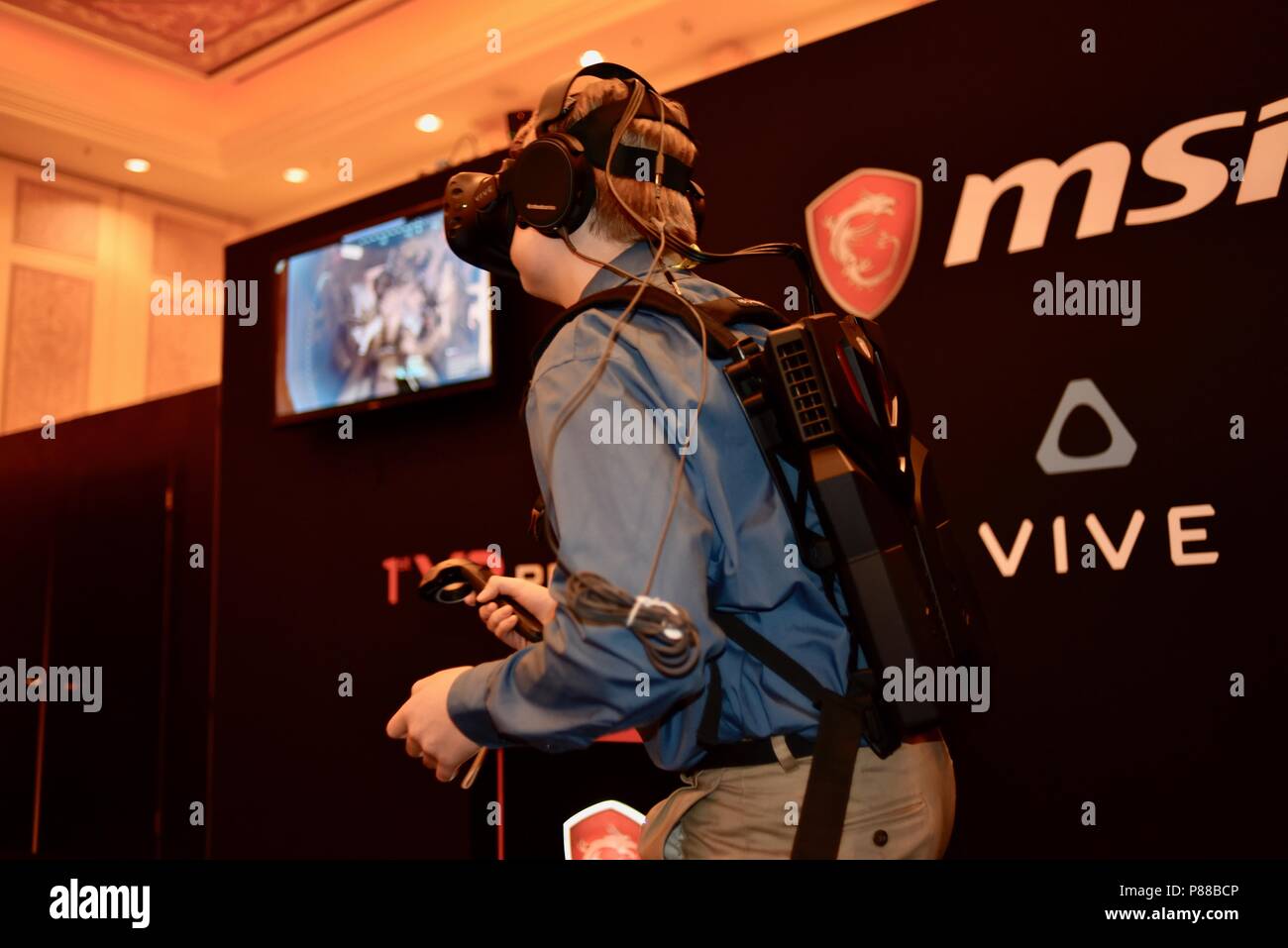 CES (Consumer Electronics Show) trade show attendee trying out game with wearable MSi computer-in-backpack with HTC Vive virtual reality VR  headset. Stock Photo