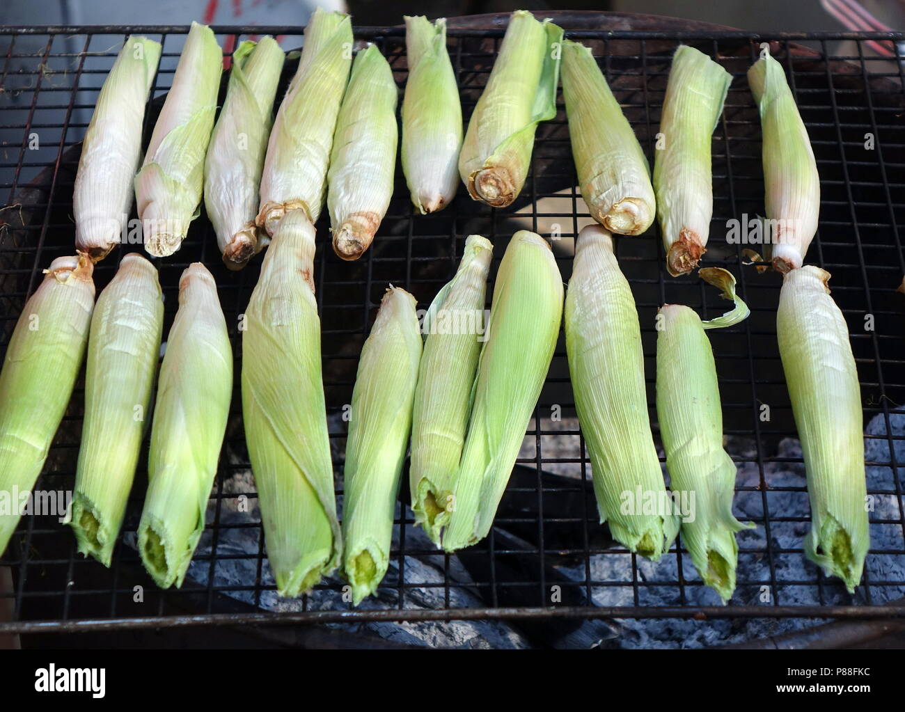 Baby corns are cooked on a charcoal grill Stock Photo