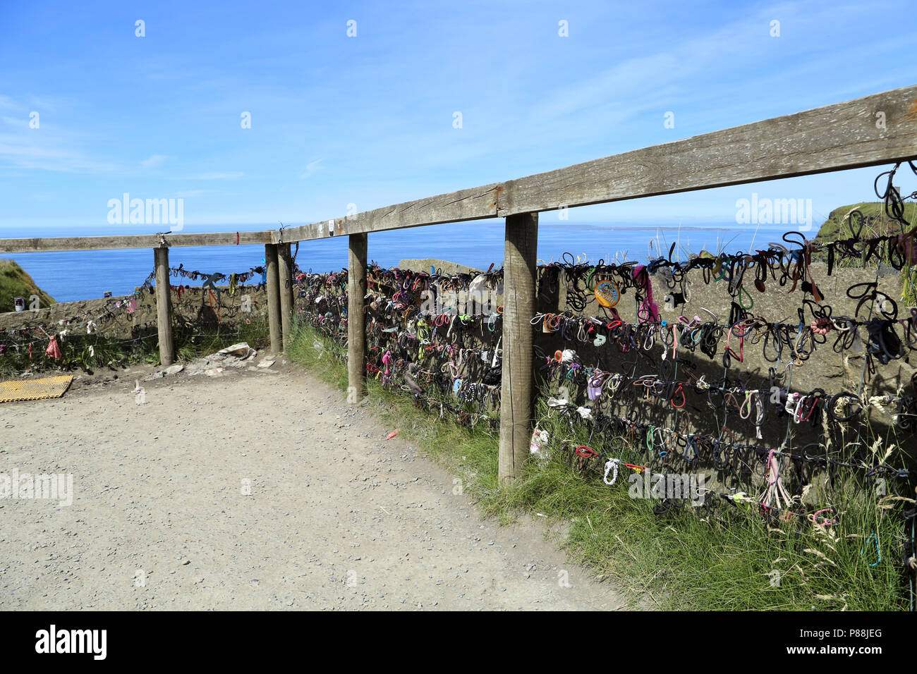 Hair ties adorn a fence along the Cliffs of Moher.The Cliffs of Moher are soaring sea cliffs located at the southwestern edge of the Burren region in  Stock Photo